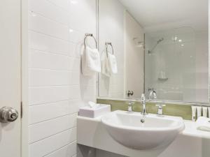 a white bathroom with a sink and a mirror at Mercure Rockhampton in Rockhampton