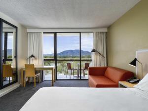 a hotel room with a bed and a desk and a view at Mercure Rockhampton in Rockhampton
