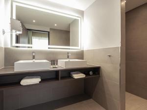 Un baño con dos lavabos y un espejo. en Novotel Duesseldorf Airport, en Düsseldorf 47 fotos más