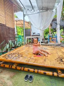 a little girl sitting on top of a wooden table at Suan's Nook Guest House in Larena +13 photos