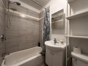 ein weißes Badezimmer mit einem Waschbecken, einer Badewanne und einem Waschbecken in der Unterkunft FULL KITCHEN 10min from DTOWN Room B in Montreal
