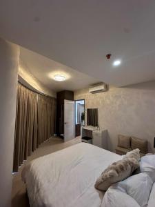 a bedroom with a large white bed and a kitchen at Cozy 1-BR Condo Unit in Mandaue City