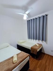 a room with two beds and a ceiling fan at Apartamento aconchegante in Maringá +12 photos
