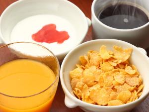 a table with a bowl of cereal and a glass of orange juice at Hakuba Tsugaike Sunrise Tanne in Otari