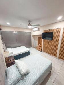 a room with two beds and a tv and a couch at Casa CAXTUS in Brasilito