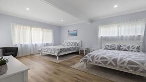 een witte slaapkamer met 2 bedden en een bank bij 30 Curlew Avenue Hawks Nest in Hawks Nest