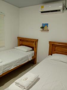 two beds in a room with white sheets and towels at Casa Isabel in Santa Cruz de Mompox