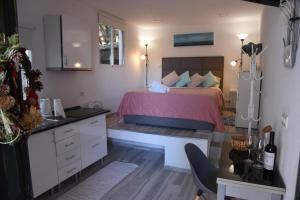 a bedroom with a bed with a pink bedspread and a desk at Tabua Village Madeira Suite VIP in Ribeira Brava