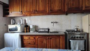 a kitchen with wooden cabinets and a stove and a microwave at Casa playa Quequen a dos cuadras del mar in Quequén
