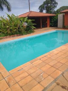 een blauw zwembad met een huis op de achtergrond bij Hotel fazenda Monte Verde in Uberlândia