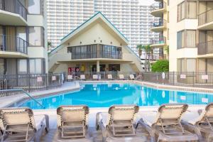 a swimming pool with chairs and a building at Amazing View Beach Front King Bed in Panama City Beach