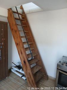 eine Holztreppe in einem Zimmer mit einer weißen Wand in der Unterkunft Kitnet Micro Sobrado in Telêmaco Borba