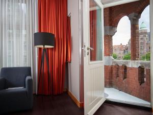 a room with a red curtain and a chair and a window at Swissôtel Amsterdam in Amsterdam