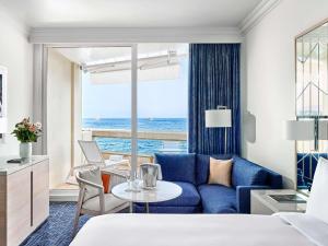 a hotel room with a blue couch and a view of the ocean at Fairmont Monte Carlo in Monte Carlo +181 photos