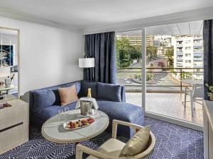 a living room with a blue couch and a table at Fairmont Monte Carlo in Monte Carlo