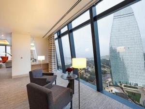 a room with two chairs and a table and large windows at Fairmont Baku, Flame Towers in Baku