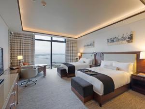 ein Hotelzimmer mit zwei Betten und einem Schreibtisch in der Unterkunft Fairmont Baku, Flame Towers in Baku