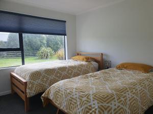 two beds in a room with a large window at Homestead Hideaway in Ohoka in Ohoka