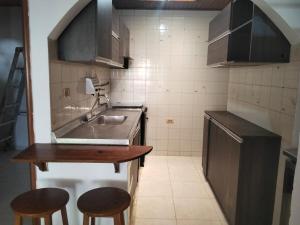 a small kitchen with a sink and two bar stools at Apartamento a 15 Min del centro in Cartagena de Indias
