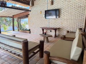a living room with a tv on a brick wall at Oceana Suites Vila da Mata in Pipa