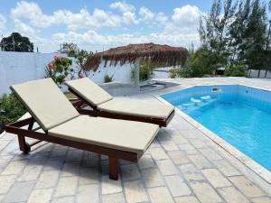 a pair of lounge chairs next to a swimming pool at Oceana Suites Vila da Mata in Pipa