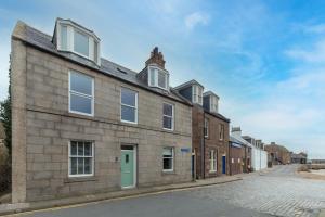 an old brick building with a green door on a street at Stonehaven ground floor home with a spectacular harbour view. in Stonehaven