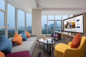 een woonkamer met een bank en een tv bij Hampton by Hilton Hefei Binhu in Hefei