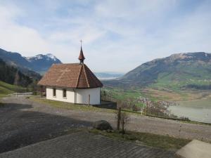 a small church with a cross on top of a hill at Biohof Langberg in Lauerz