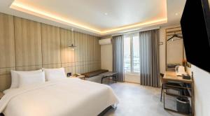 a bedroom with a large white bed and a television at browndot 서천 