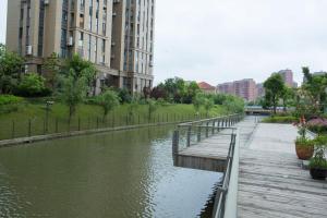 a river with a wooden walkway next to some buildings at Huayi Hotel in Shanghai