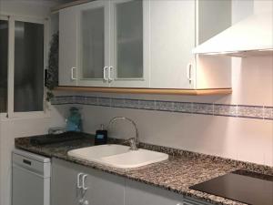 a kitchen counter with a sink and white cabinets at Encalma Vacacional El Ático in Puerto de Sagunto +36 photos