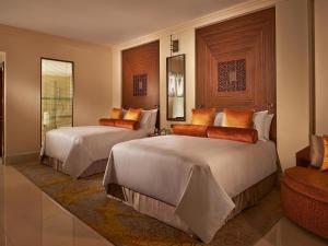 a hotel room with two beds and a chair at Fairmont The Palm in Dubai