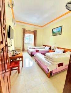 a hotel room with three beds and a television at Khách Sạn Mai Đào in Mèo Vạc +1 photo