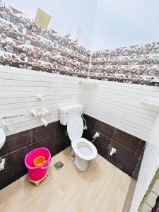 a bathroom with a toilet and a pink bucket at Bala ji guest house in Vrindāvan