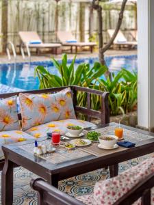 Grace Boutique Resort في موي ني: طاولة عليها أطباق من الطعام بجوار حمام سباحة