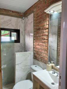 La salle de bains est pourvue de toilettes blanches et d'un mur en briques. dans l'établissement Panorámica Sierras, à Villa Carlos Paz