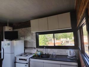 a kitchen with a sink and a refrigerator and a window at Panorámica Sierras in Villa Carlos Paz +1 photo
