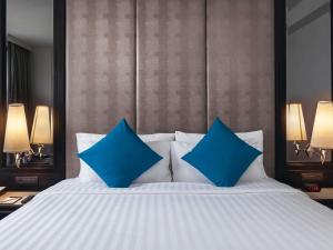 Un dormitorio con una cama con almohadas azules. en Mövenpick Hotel Sukhumvit 15 Bangkok, en Bangkok 196 fotos más