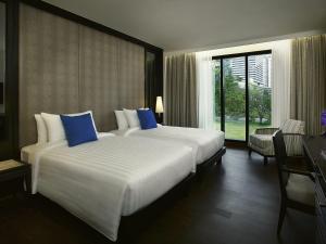 Una habitación de hotel con una cama grande con almohadas azules. en Mövenpick Hotel Sukhumvit 15 Bangkok, en Bangkok