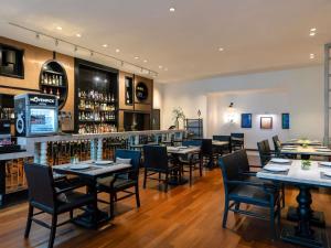 a restaurant with tables and chairs and a bar at Mövenpick Hotel Sukhumvit 15 Bangkok in Bangkok