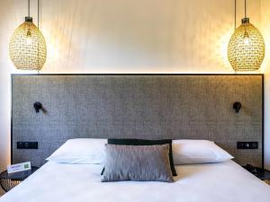 a bedroom with a white bed with two pendant lights at ibis Styles Rennes Cesson in Cesson-Sévigné +74 photos