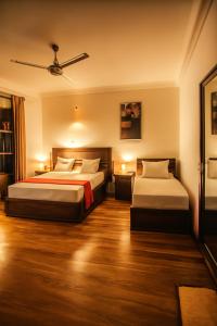 a hotel room with two beds and a ceiling fan at Pearl Paradise Villa in Awariwatta