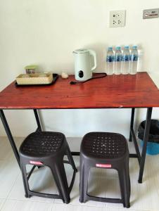Ban Khlong HiaにあるFirdous Guesthouseの木製のテーブル、椅子2脚、水のボトル