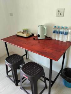 Ban Khlong HiaにあるFirdous Guesthouseの水のボトルと2脚の椅子が置かれた木製のテーブル