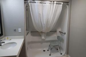 een badkamer met een douche en een stoel naast een wastafel bij Super 8 by Wyndham Savannah in Savannah