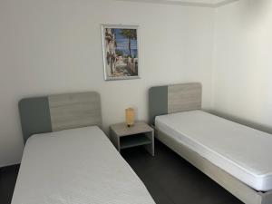 two beds in a room with a table and a picture at Clara Grace sea view in Leuca +11 photos