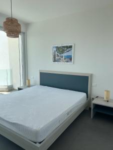 a white bedroom with a large bed and a window at Clara Grace sea view in Leuca