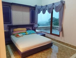 ein Schlafzimmer mit einem Bett und einem großen Fenster in der Unterkunft Sentral Villa Trawas in Trawas