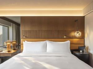 a bedroom with a large white bed with a wooden headboard at Fairmont Golden Prague in Prague