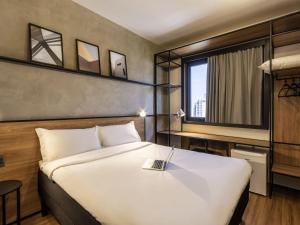 a bedroom with a large white bed and a window at ibis Ponta Grossa in Ponta Grossa